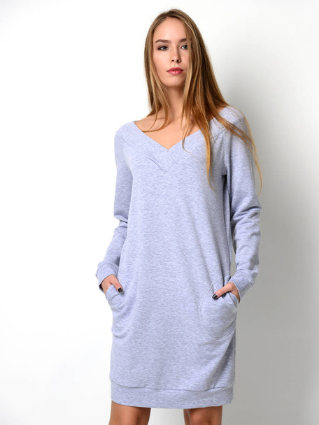 Young beautiful woman posing in new fashion grey winter dress blouse on a gray  - Фото, зображення