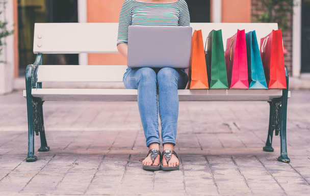 Cropped shot of woman using laptop outdoor on a   bench for online shopping - Foto, imagen