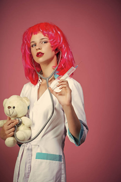 Health care and cure concept. Nurse in red wig on pink background - Valokuva, kuva