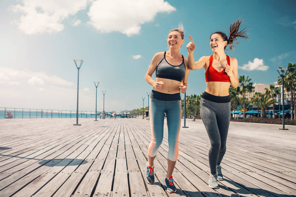 Excited girls jogging along the seaside - Photo, Image