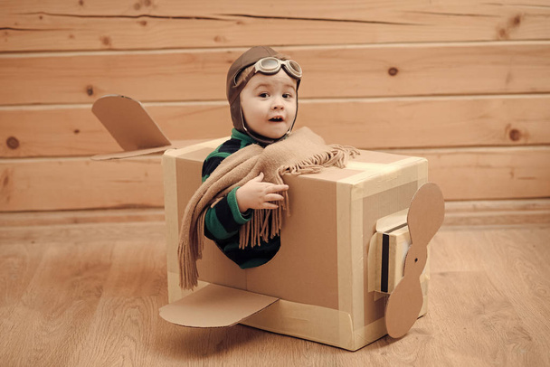 give the child a dream. Eight-year boy playing with a cardboard airplane - Φωτογραφία, εικόνα