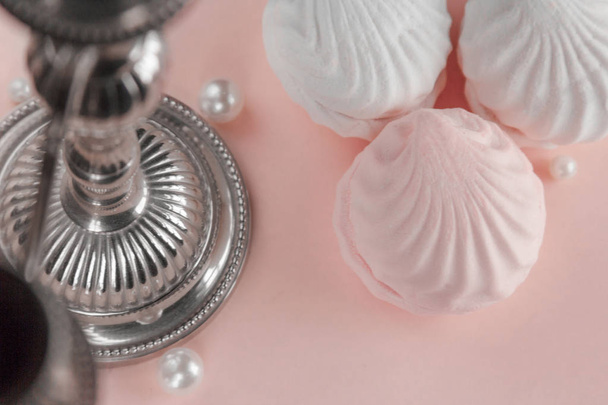 Tres piezas de zephyr sobre un fondo de color pastel rosado con candelero, perlas y dimendras alrededor. Malvaviscos caseros sobre la mesa. Primer plano
. - Foto, Imagen