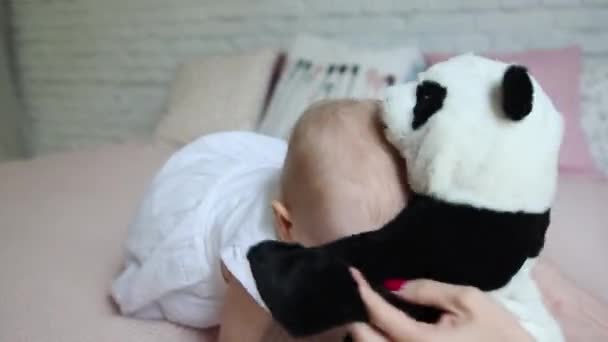 Happy young mother and her girl with play on bed with toy Panda bear home smiling. - Materiał filmowy, wideo