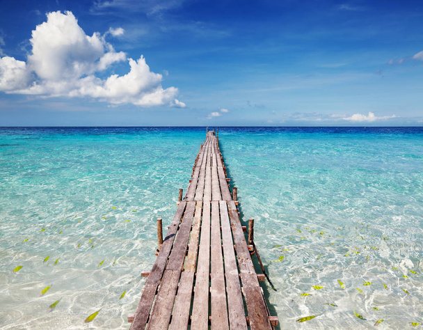 Fából készült móló, egy trópusi szigeten, a kristálytiszta tenger és a kék ég - Fotó, kép