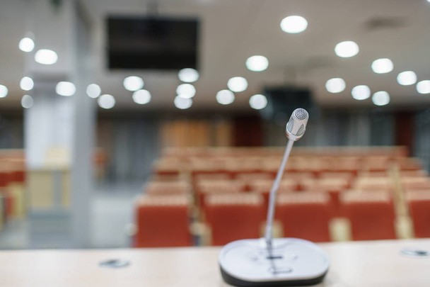 Mikrofon im Vordergrund. Seminarvortrag. Konferenzraum voller leerer Sitze. rote Farbe. Halle für Workshops und Seminare - Foto, Bild