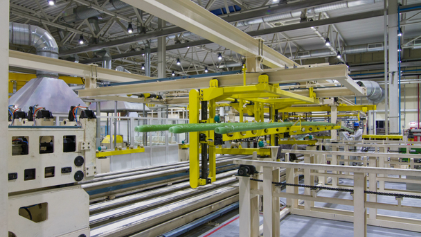 timelapse huge conveyor tranfers long green plastic pipes workers control process in brightly lit workshop - Footage, Video