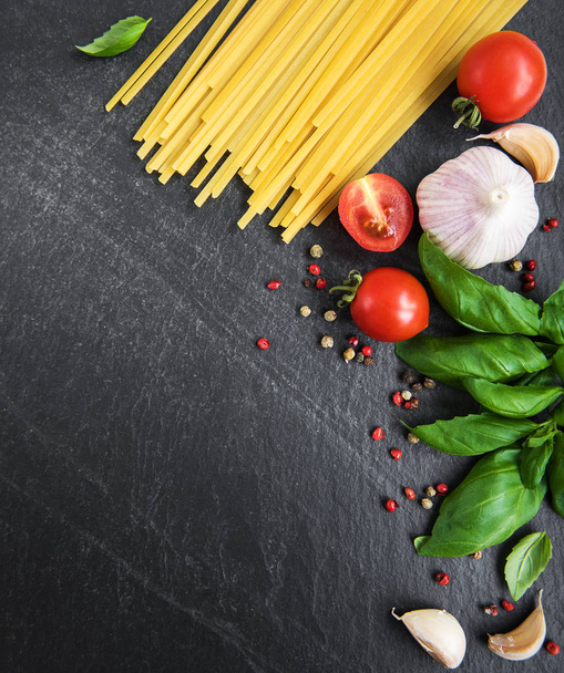 Italian food ingredients. Pasta, tomatoes, basil and spices on a black background - Φωτογραφία, εικόνα