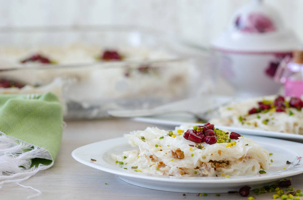 Traditional Ramadan Dessert Gullac on the table. It is made with gullac, milk, rose water, walnut, vanilla. It is decorated with pomegranate  and pistachio. - Photo, Image