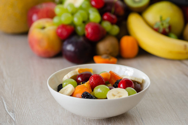 Zdravý Čerstvý ovocný salát v popředí, barevné ovoce, v pozadí. - Fotografie, Obrázek