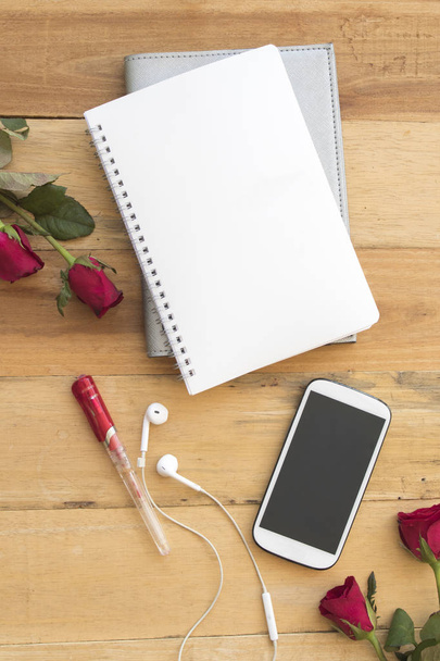 telefon komórkowy i planista notebook z układania kwiatów róż na tle drewna - Zdjęcie, obraz