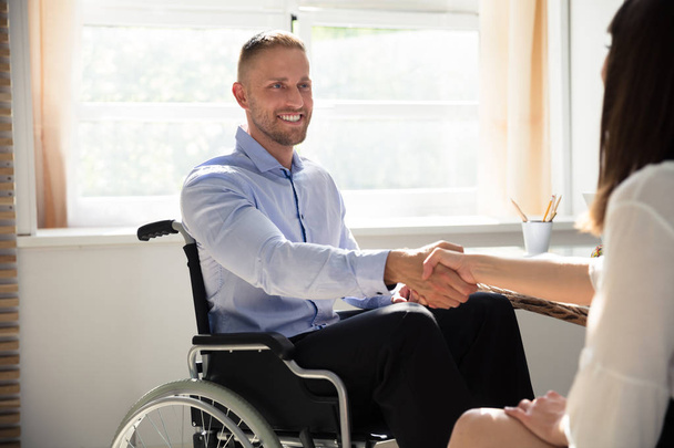 Happy Disabled Businessman Sitting On Wheelchair Shaking Hand With His Partner - Foto, afbeelding