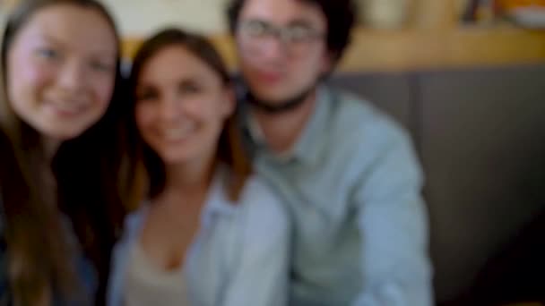 Tres amigos se sientan en un café, se divierten comunicándose y hacen selfies. Movimiento lento
 - Imágenes, Vídeo