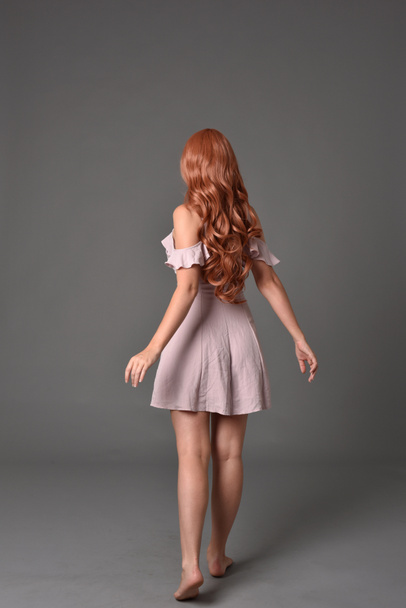 Ganzkörperporträt eines Mädchens im rosa Sommerkleid. Stehende Pose auf grauem Studiohintergrund - Foto, Bild
