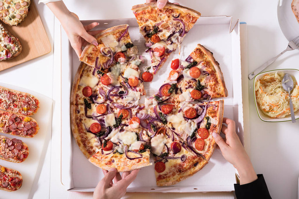 Friends Picking Slice Of Pizza From Box On Table - Foto, Imagen