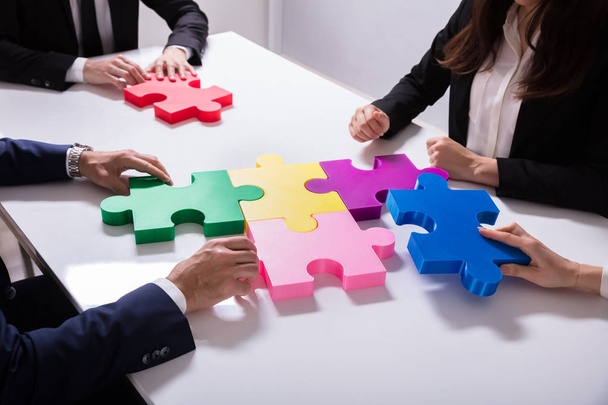 Grupo de Empresarios Resolviendo rompecabezas multicolor en el escritorio
 - Foto, Imagen