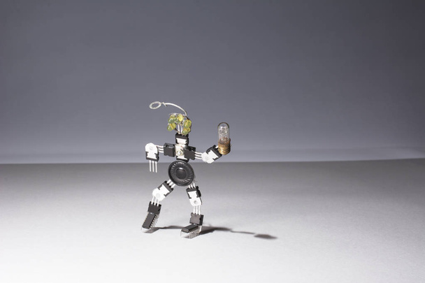 Robot drôle et mignon de microcircuits avec une ampoule dans les mains sort de la carte pour les inventions dans le domaine de l'électronique
 - Photo, image
