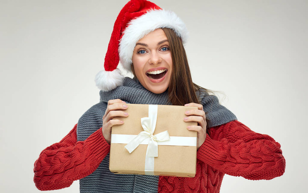 Smiling woman wearing christmas hat holding paper gift box and looking at camera  - Photo, image