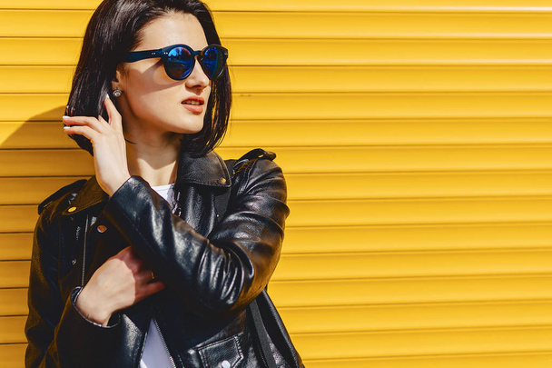Beautiful girl sunglasses on bright yellow background outside - Photo, image