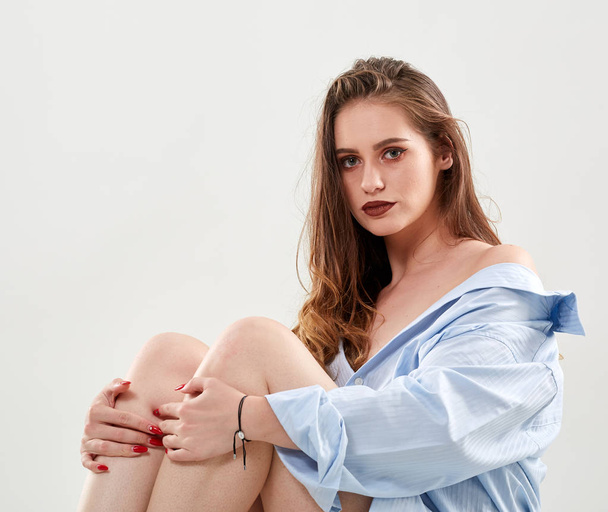 Young glamour female model with brown hair sitting and looking at camera - Foto, afbeelding