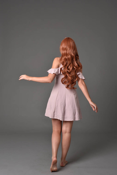 retrato de comprimento total da menina vestindo vestido de verão rosa. em pé pose no fundo do estúdio cinza
 - Foto, Imagem