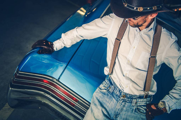 Fiatal Cowboy vezető és a klasszikus izom-autó. Amerikai stílusú vezetés. - Fotó, kép