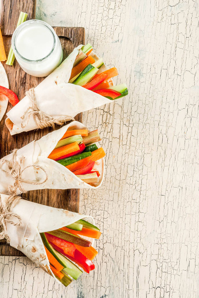 Summer healthy snack appetizer, Mexican style tortilla sandwich wraps assorted colorful fresh vegetable sticks (celery, rhubarb, pepper, cucumber and carrot) with yoghurt sauce dip above - Photo, Image
