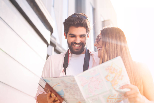 Happy couple with map choosing first destination in sunny Europe city - 写真・画像