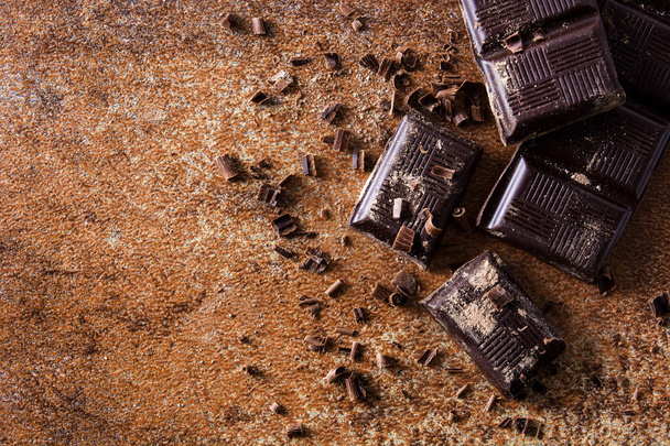 Chocolate pieces on brown background. Top view. Copyspace - Фото, изображение