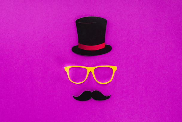 Κάτοψη των κυρίων πρόσωπο φτιαγμένο από χαρτόνι γυαλιά, μουστάκι και καπέλο σε ροζ επιφάνεια - Φωτογραφία, εικόνα