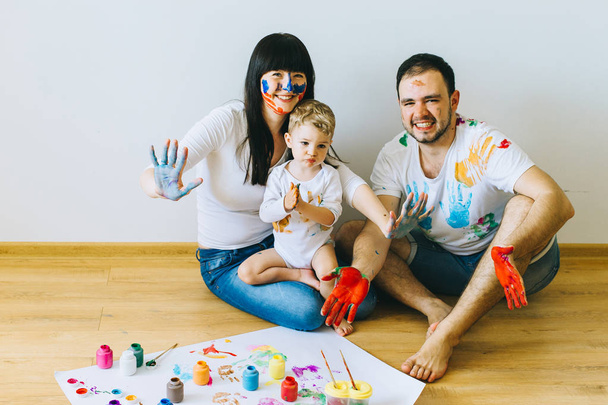 happy family painting a poster and one another with paints - Zdjęcie, obraz