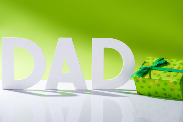 green gift box near dad inscription made of white letters on green, Happy fathers day concept - Foto, Imagem