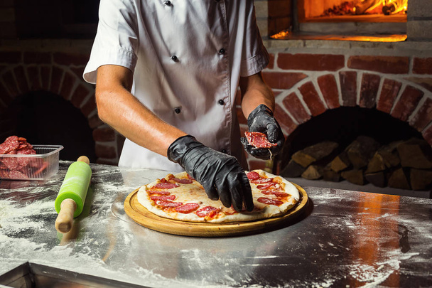 Cook (Chef) making delicious pizza at the restaurant, close-up - Photo, Image