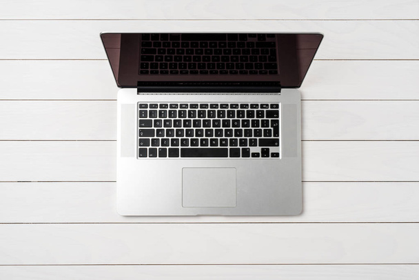 Overhead shot of modern laptop on white wooden table - Foto, Imagem