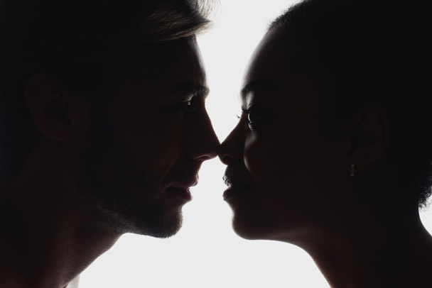 vue latérale de silhouettes de couple interracial amoureux se regardant
 - Photo, image