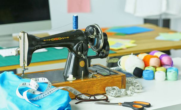 Ретро швейная машина на рабочем столе дизайнера одежды
 - Фото, изображение