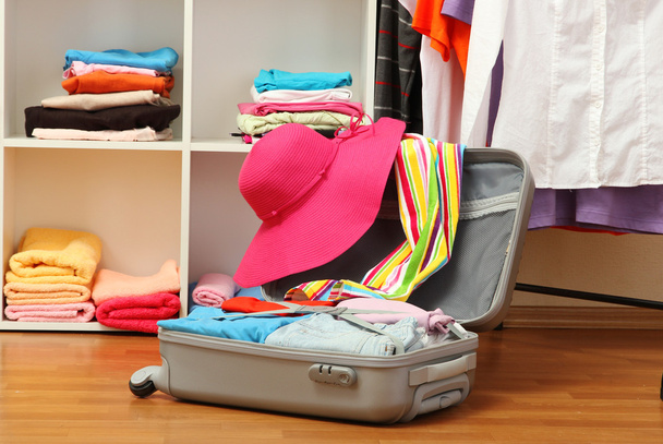 Open silver suitcase with clothing in room - Foto, Bild