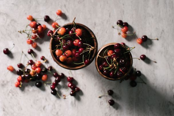 top view of fresh ripe healthy cherries in bowls on marble surface - Foto, Bild