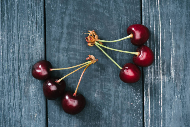 top view of ripe sweet cherries on rustic wooden surface - Photo, Image