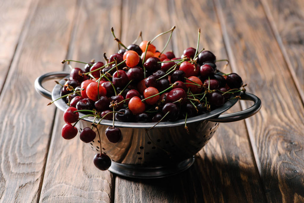 друшляк зі свіжими стиглими солодкими вишнями на сільському дерев'яному столі
 - Фото, зображення