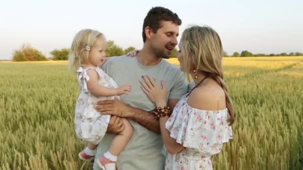 Familia joven y feliz con un niño en el fondo de un campo de trigo
. - Imágenes, Vídeo