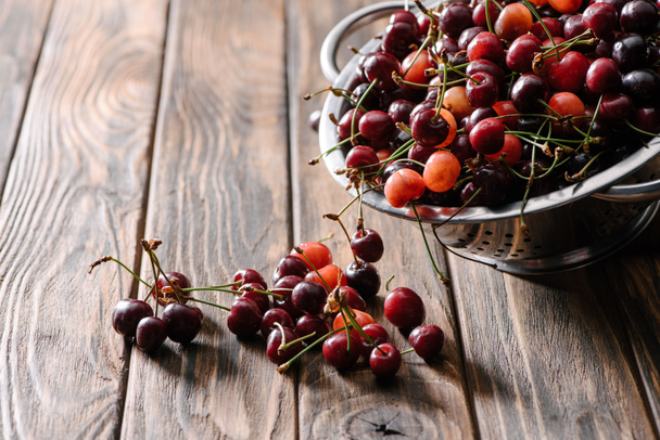 colador con cerezas dulces frescas y maduras sobre mesa de madera
 - Foto, Imagen