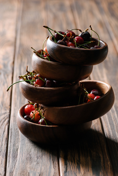 cuencos apilados con cerezas frescas maduras sobre mesa de madera
 - Foto, Imagen