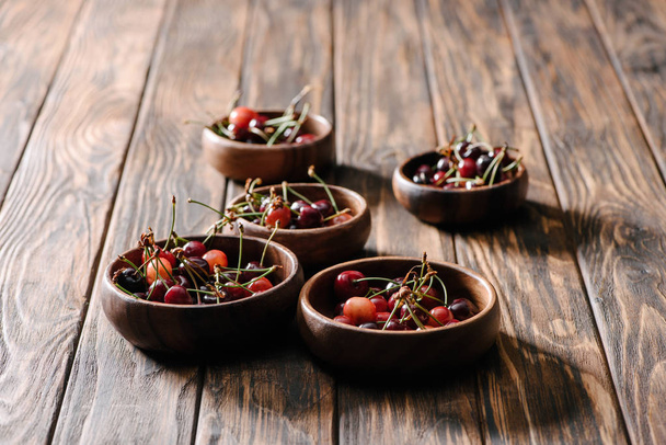 fresh ripe sweet cherries in bowls on wooden table - 写真・画像