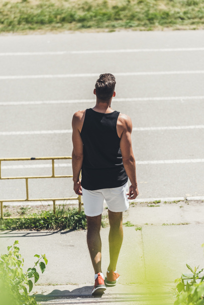 back view of young male jogger going on running track  - Foto, Bild