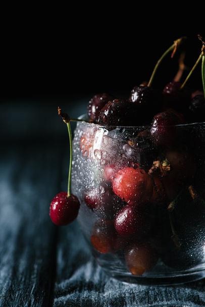 close-up view of ripe sweet cherries in wet glass on wooden table  - Φωτογραφία, εικόνα