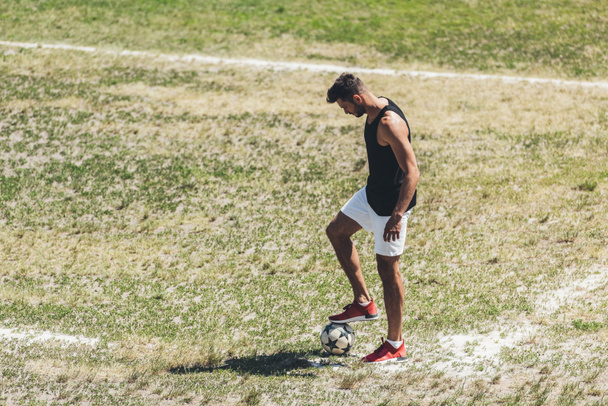 mannelijke voetballer met voetbal bij Speeltuin veld  - Foto, afbeelding