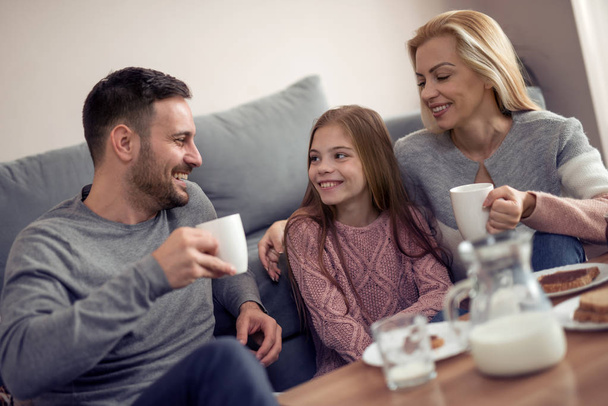 Семья из трех человек завтракает утром вместе в своем доме
. - Фото, изображение