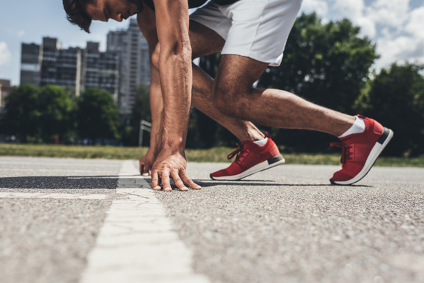 Teilsicht männlicher Sprinter in Startposition auf Laufstrecke  - Foto, Bild