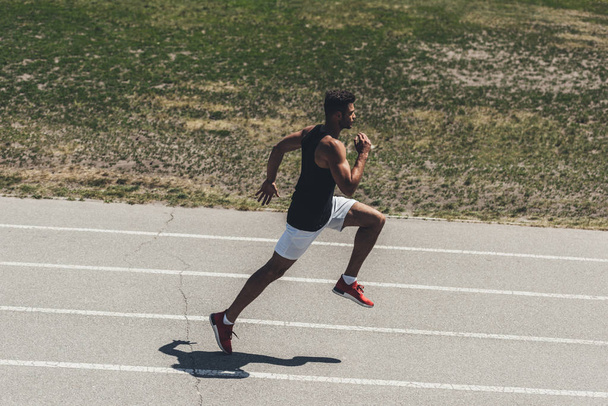 высокий угол обзора спортсмена, бегущего по легкой атлетике на спортивной площадке
 - Фото, изображение