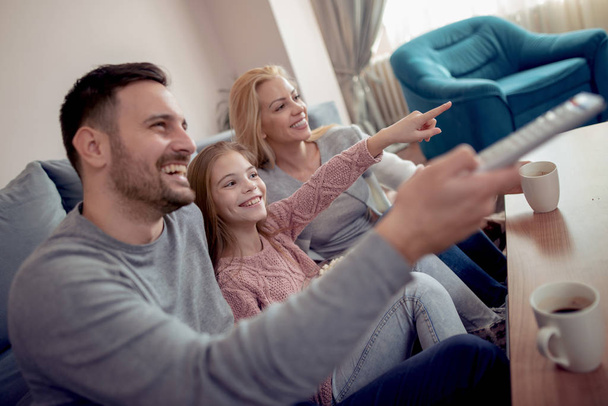 Young family watching TV together at home and having fun together. - Valokuva, kuva